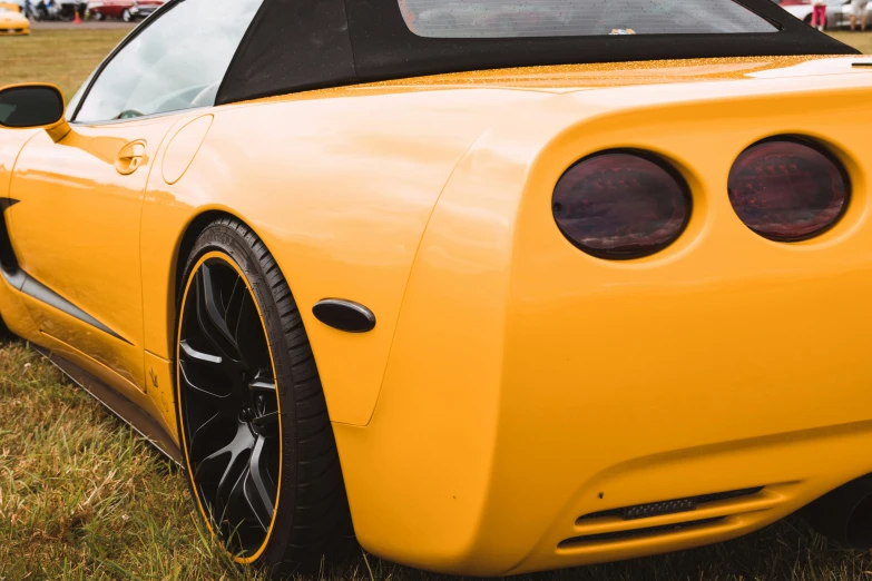 the front end of a yellow car with black wheels