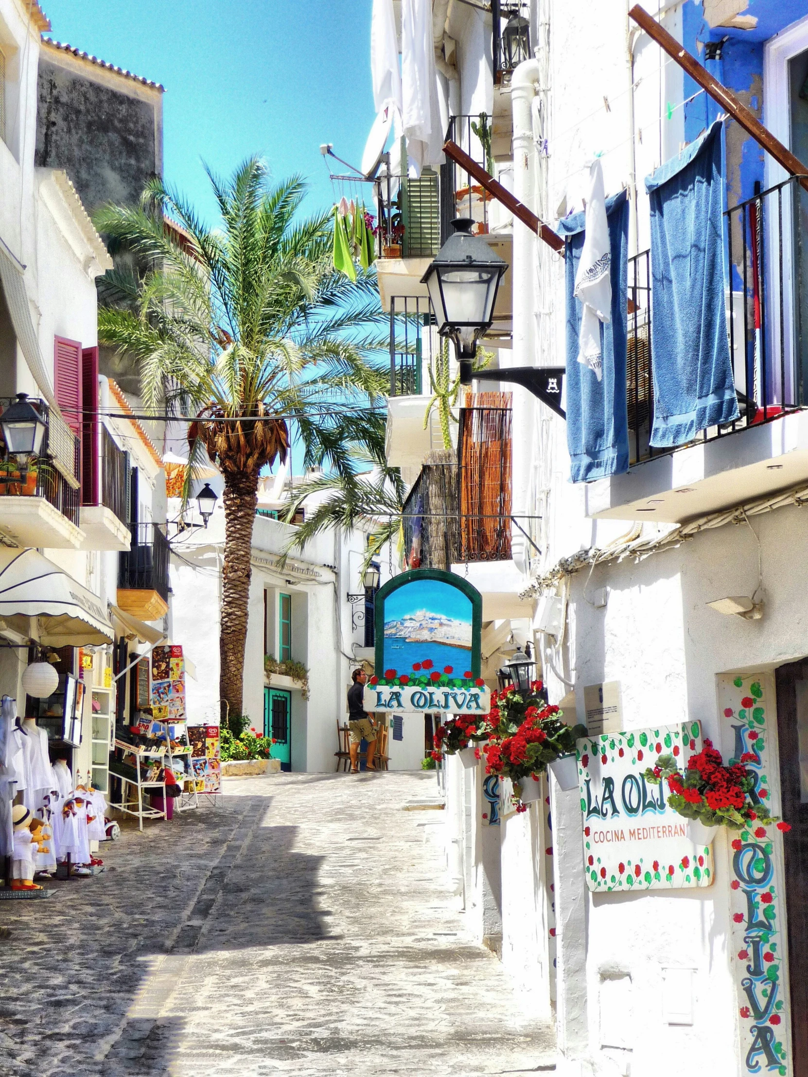 narrow stone street with shops lining it in the shade