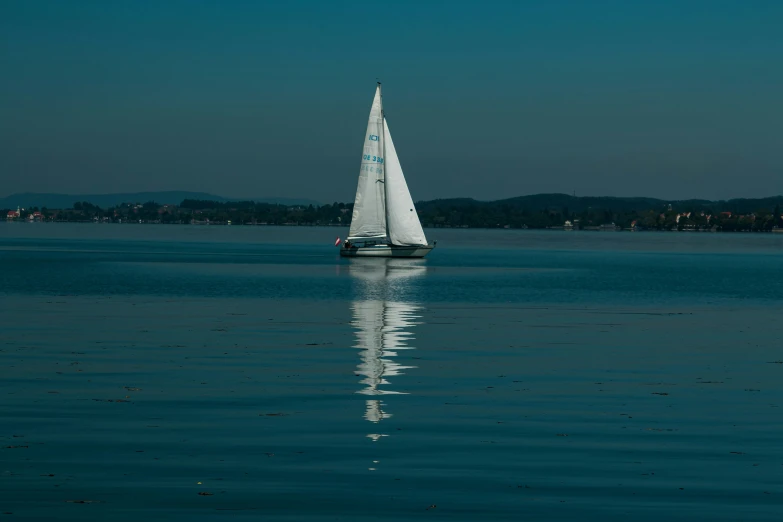 sail boat out on water with houses and mountains in background