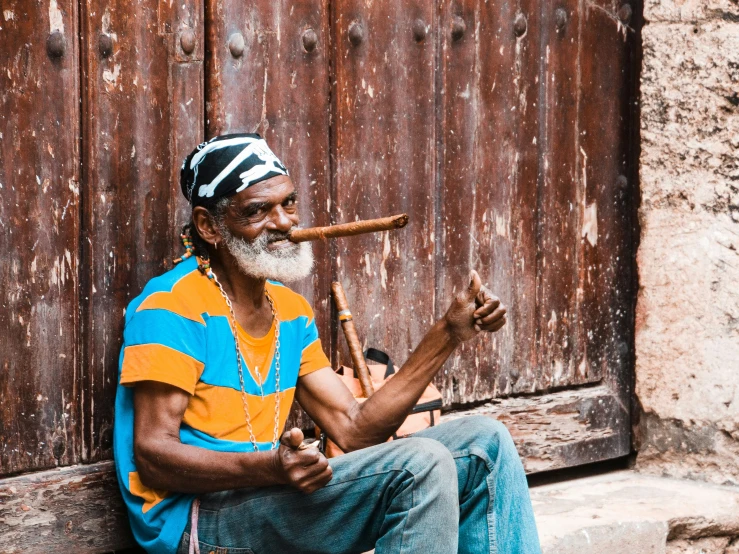 a man with an umbrella, sitting on the steps smoking cigar