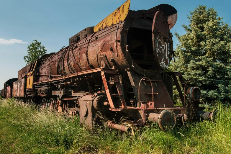 an old train sits on some tracks in the middle of a grassy field