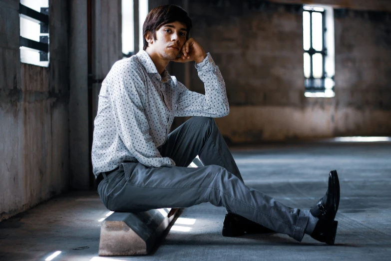 a man sitting on a stool in a room with concrete walls