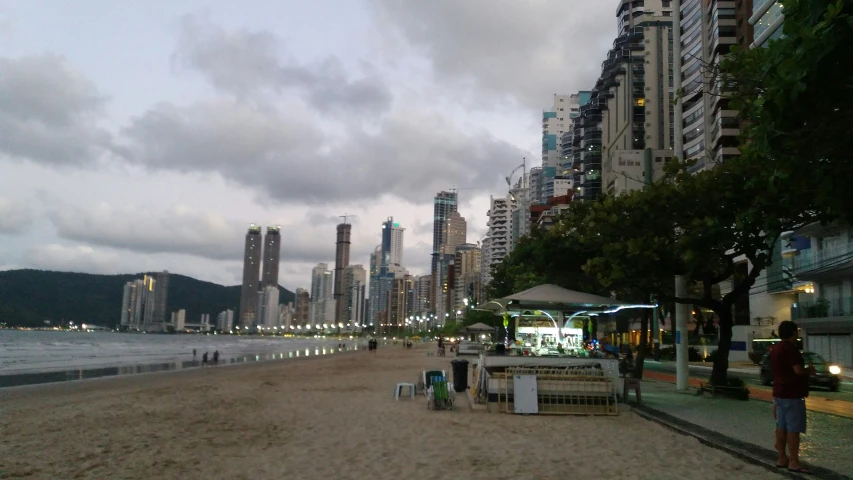 several people are walking on the sand near a harbor