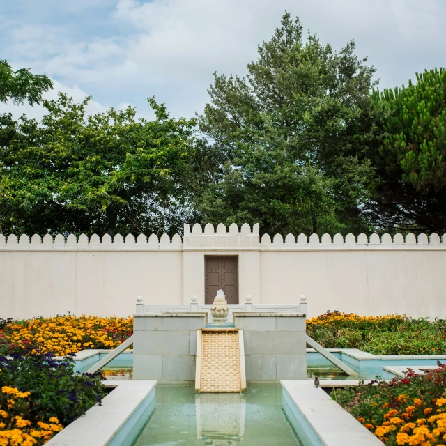 a fountain that is near some flowers and trees