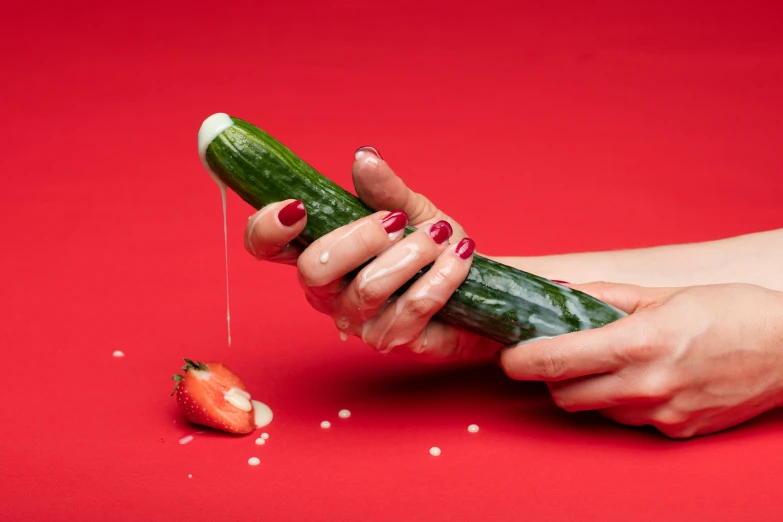 someone peeling an cucumber into pieces with a small red object on top