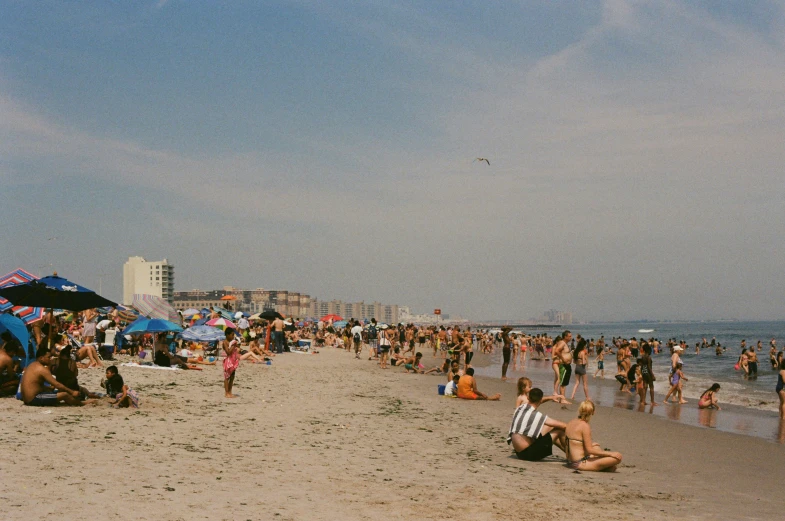 a group of people standing on top of a beach next to a blue umbrella