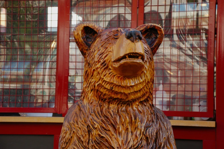 a close up of a wooden bear statue near a window