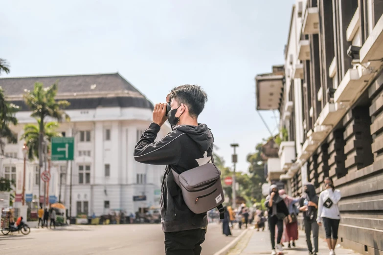 a man with a cellphone to his ear, is walking down the street