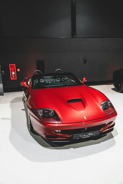 a red sports car is shown parked in a dark room