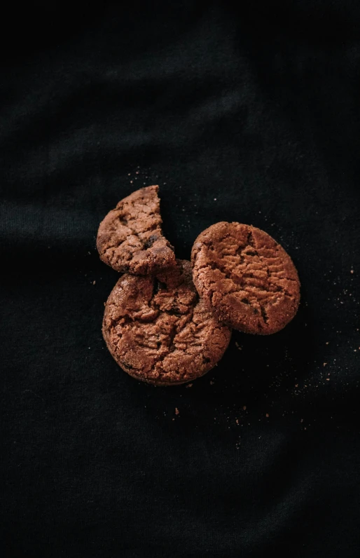 three chocolate cookies stacked high up on a black background