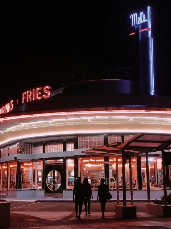 two people walking outside a restaurant at night