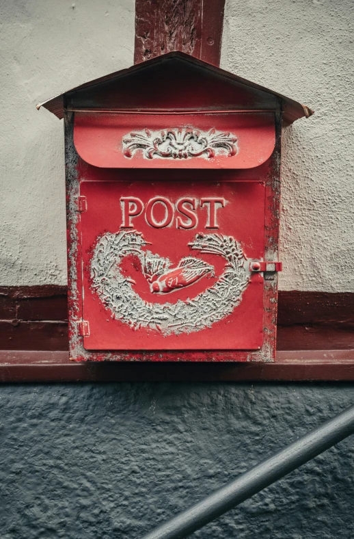 a red post box sitting next to a brick wall
