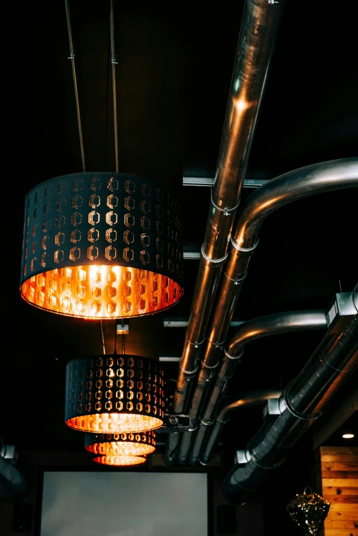 some lamps that are hanging up above some pipes