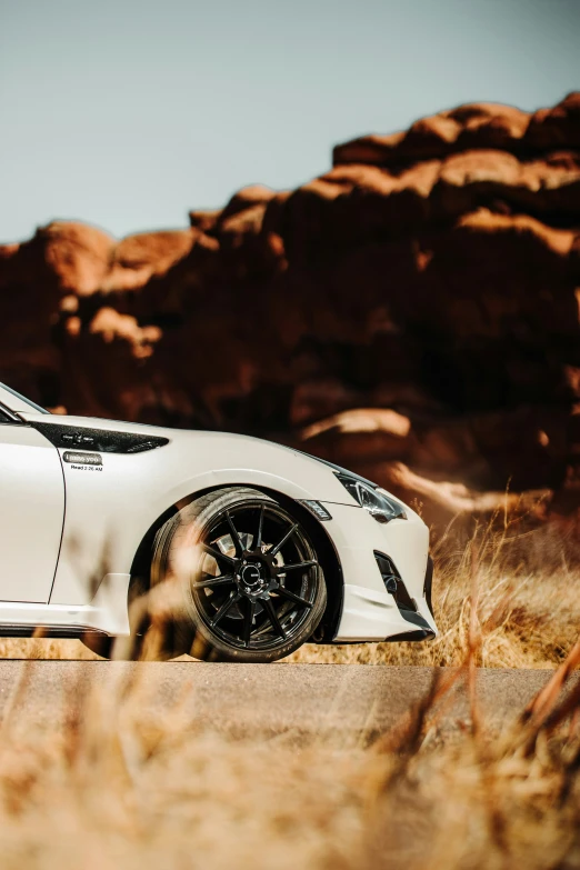 a white car in front of some rocks