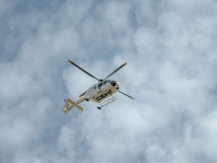 a white helicopter flying in cloudy skies