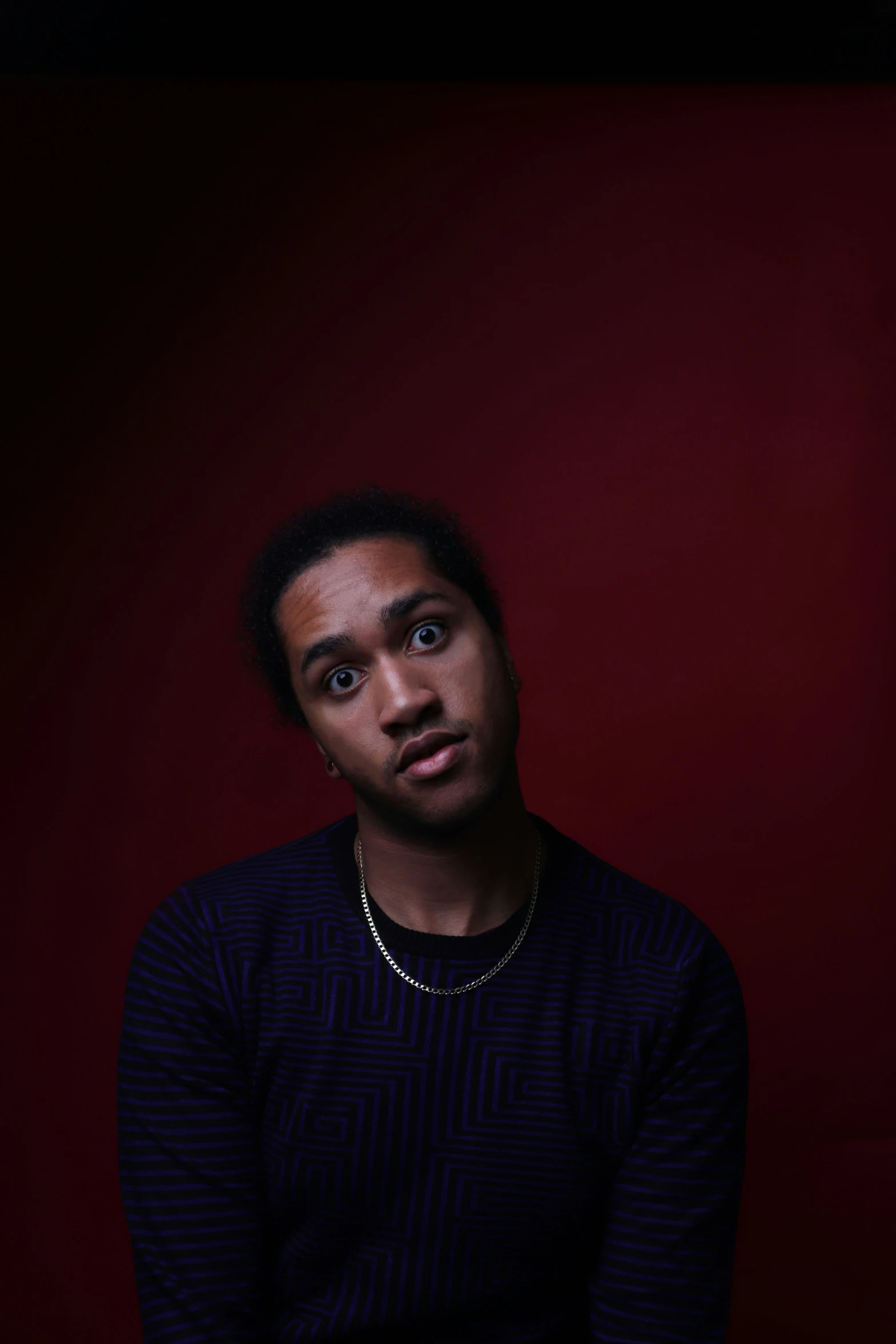 a man standing next to a dark red wall