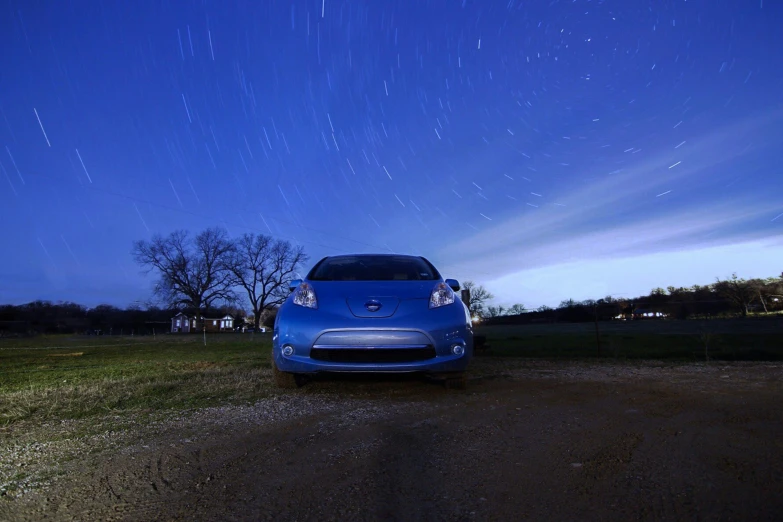 the car is parked in the grassy field near a fence