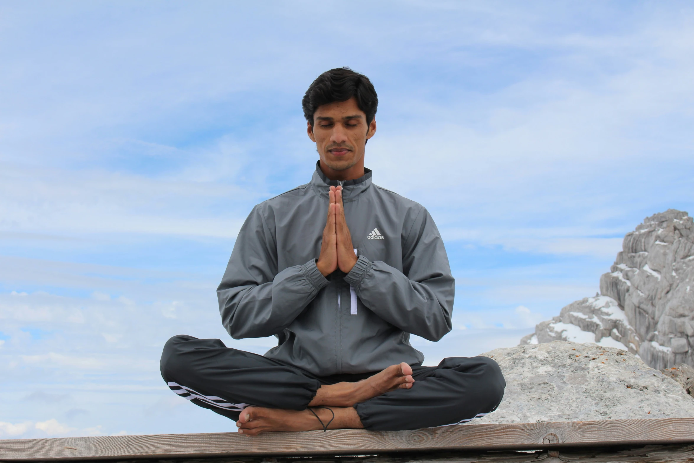 a man is doing a meditation position on the wooden planks