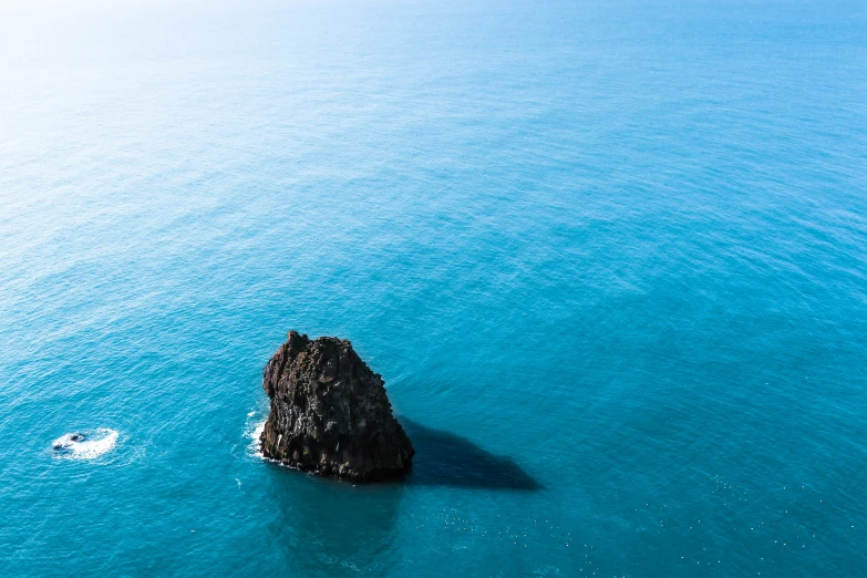 a blue ocean with large rock in the middle