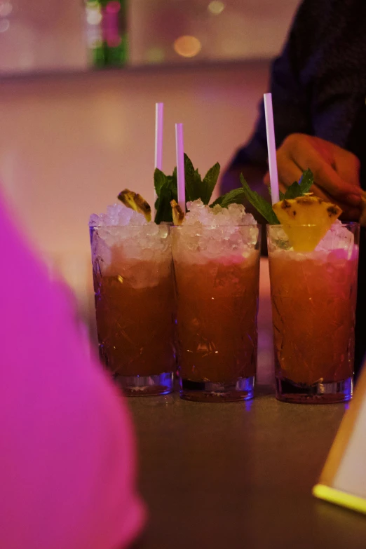 there are four glasses with different drinks on a bar