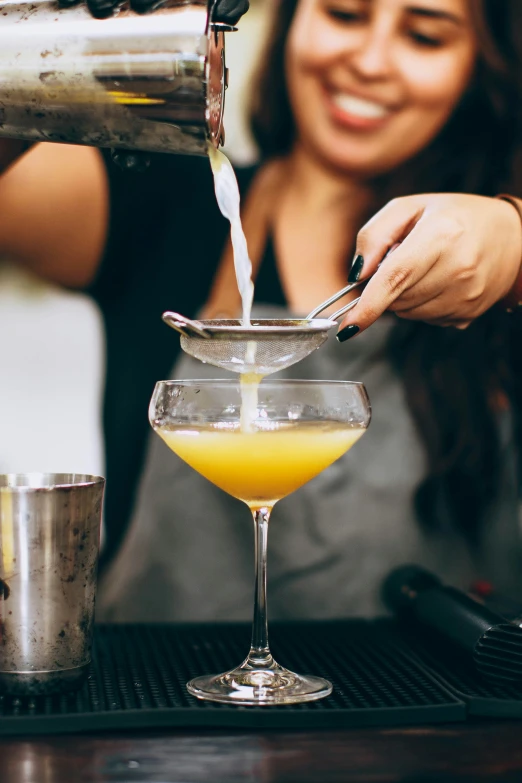 bartender pouring cocktail from pitcher to glasses at bar