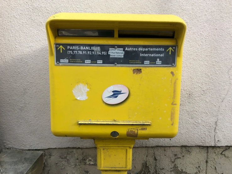 a yellow telephone box has several stickers and a circle