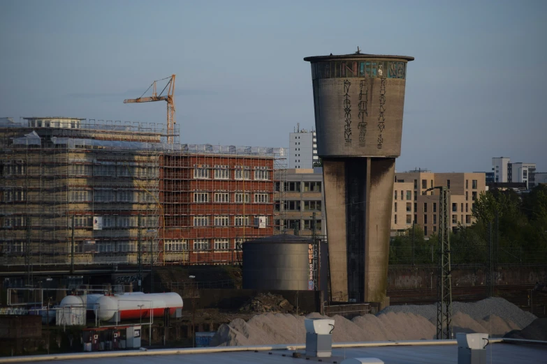 a water tower on the top of a building with crane in the background