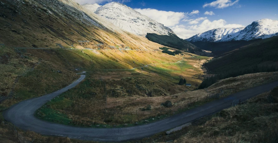 an aerial view of a road winding with mountains in the background