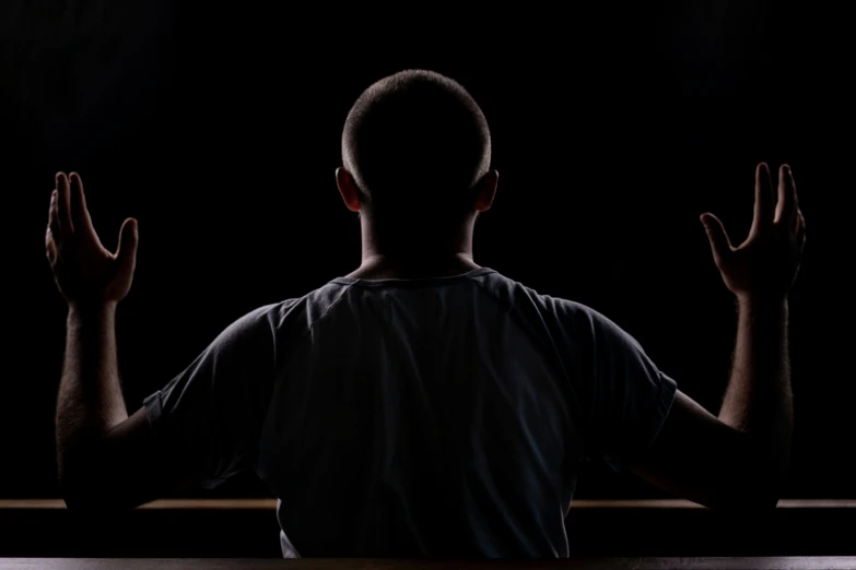 a man sitting down in front of a window in the dark