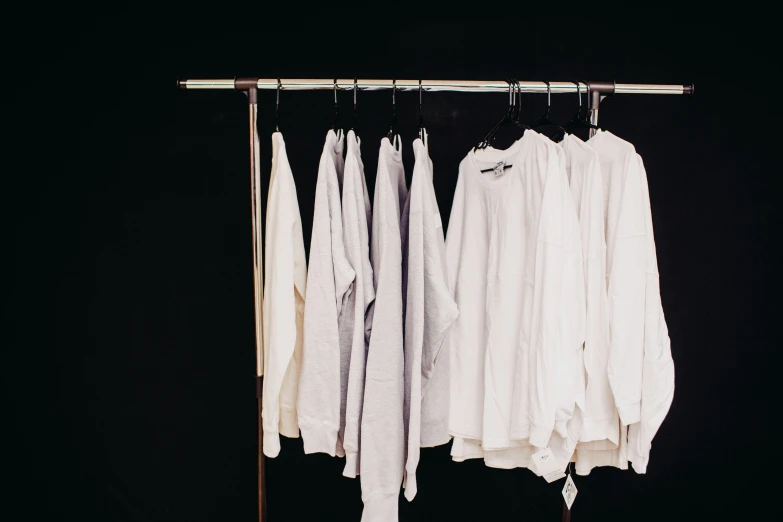 several unoned shirts hang on a rail in a room