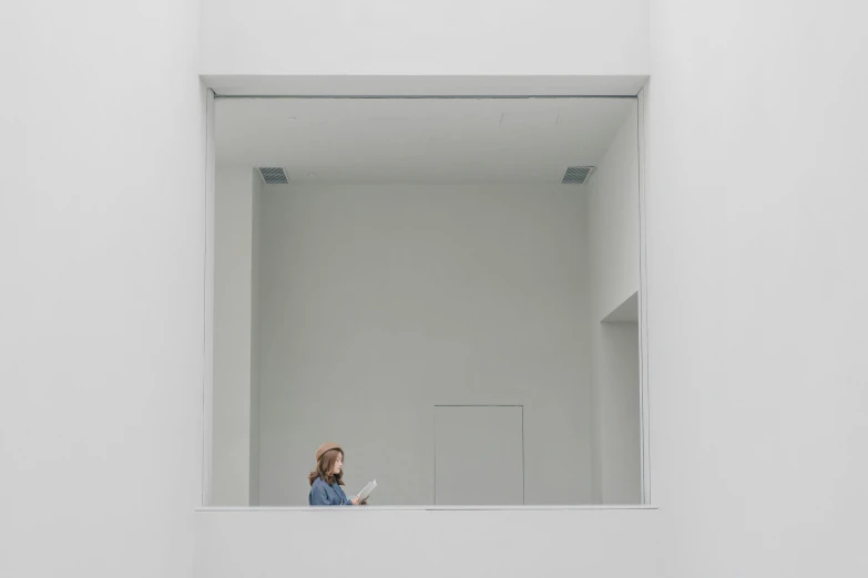 a woman standing in front of a mirror reading a book