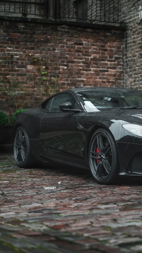 a black sport car is parked near a brick wall