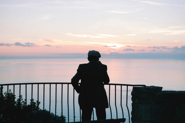 a man looking out over the ocean, from a lookout