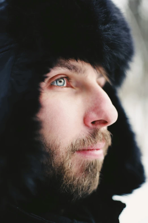 a man in a furry hat looks off into the distance