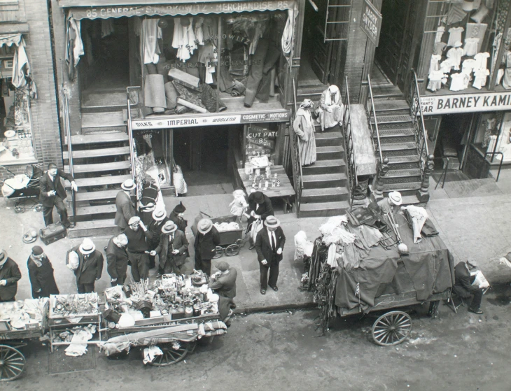 black and white pograph of men dressed in old fashioned clothes in front of a store