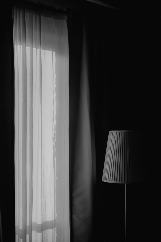 the curtains are white in color while a lamp is next to it