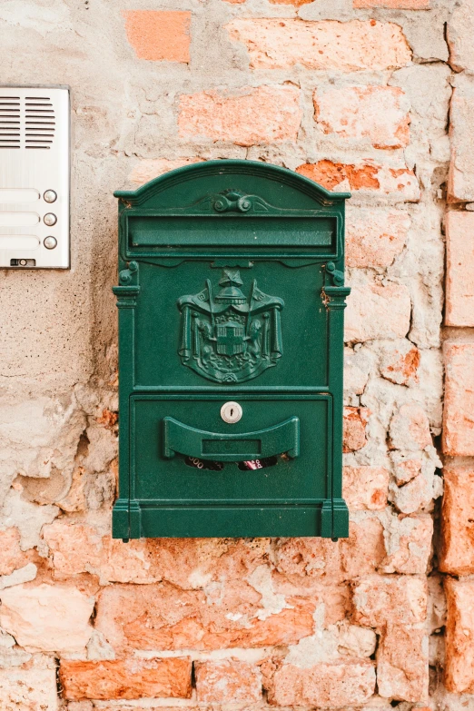 an old brick wall is painted in green and has a mail box on it