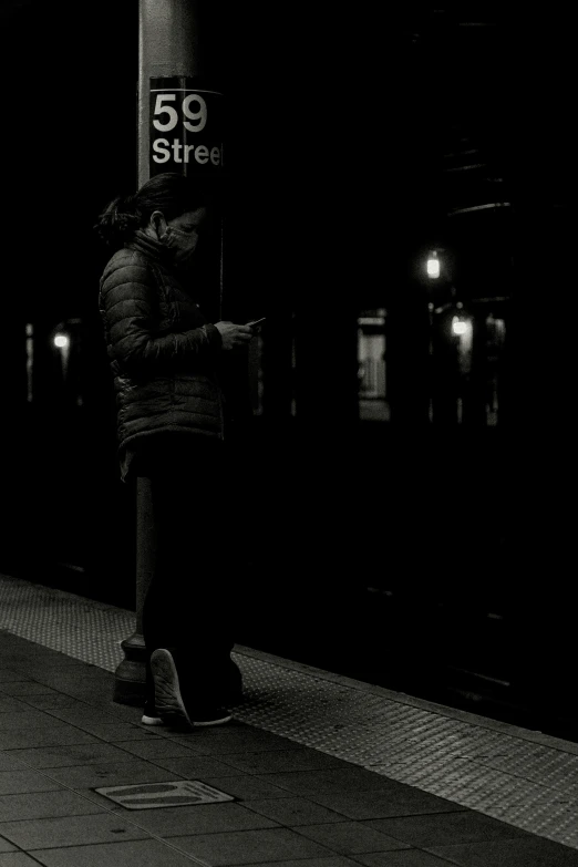 black and white pograph of person waiting for train