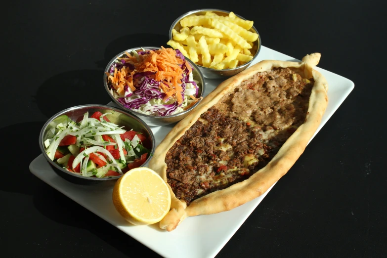 a large sausage on a tray with some salad and a bowl of chips