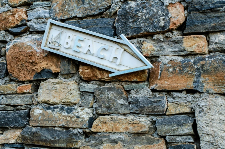 a sign hanging from the side of a stone wall