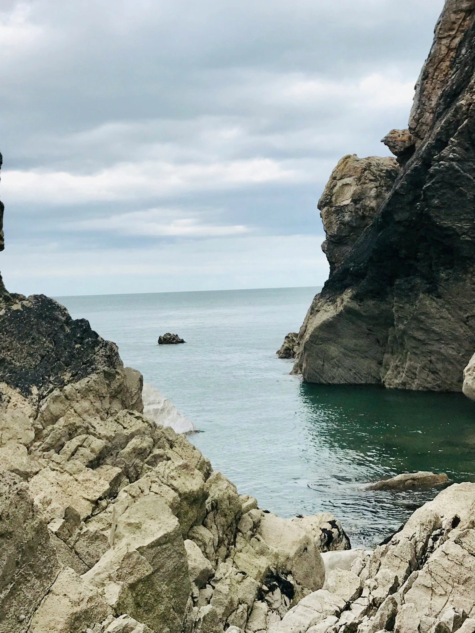 a person walking across rocks towards the ocean