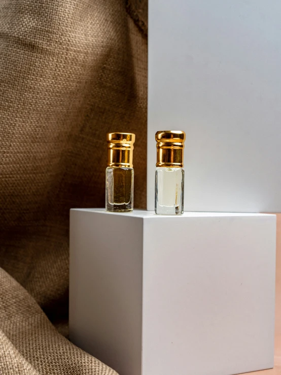 two bottles sitting on top of a white cube