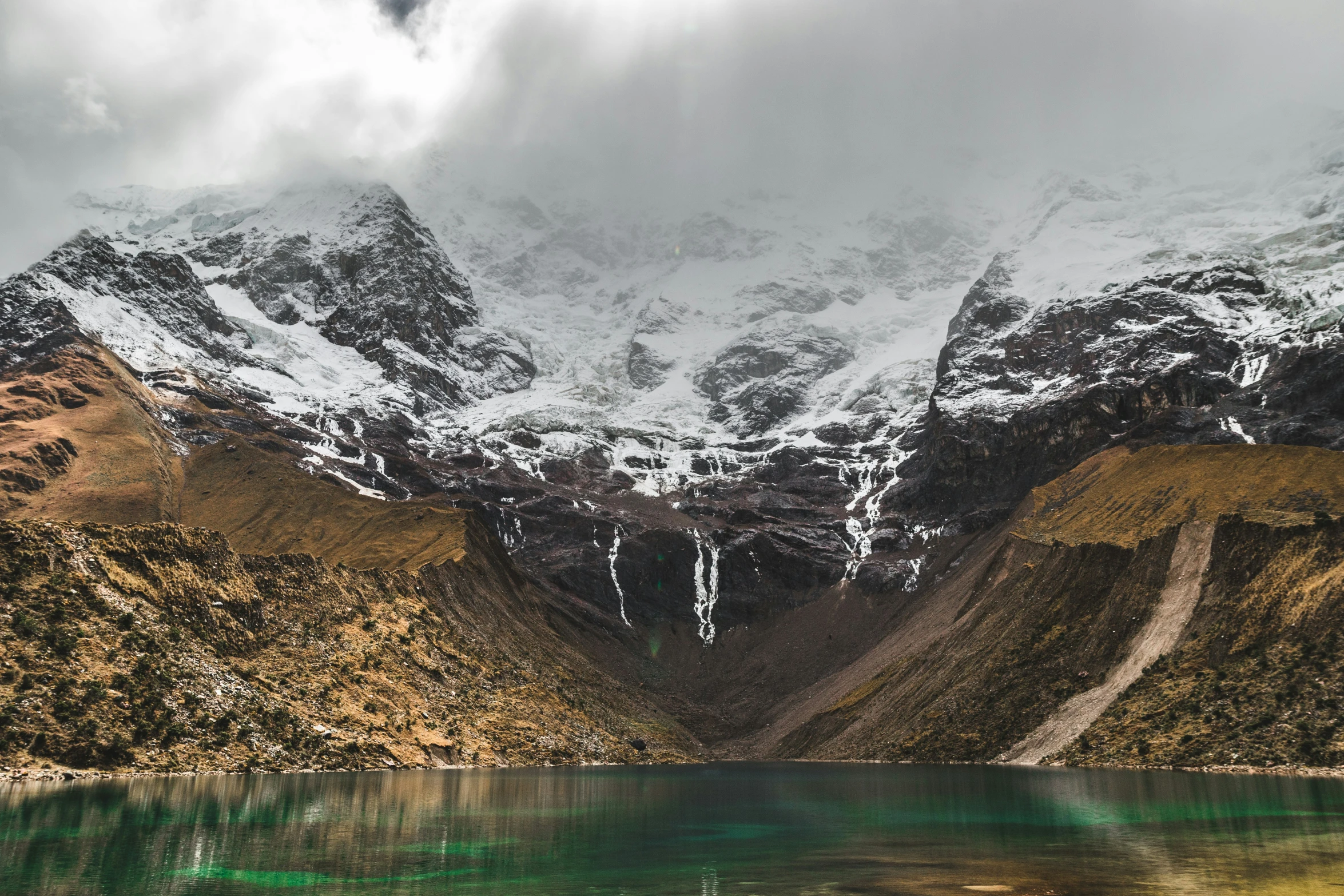 a mountain view of a body of water with snow covered mountains in the background