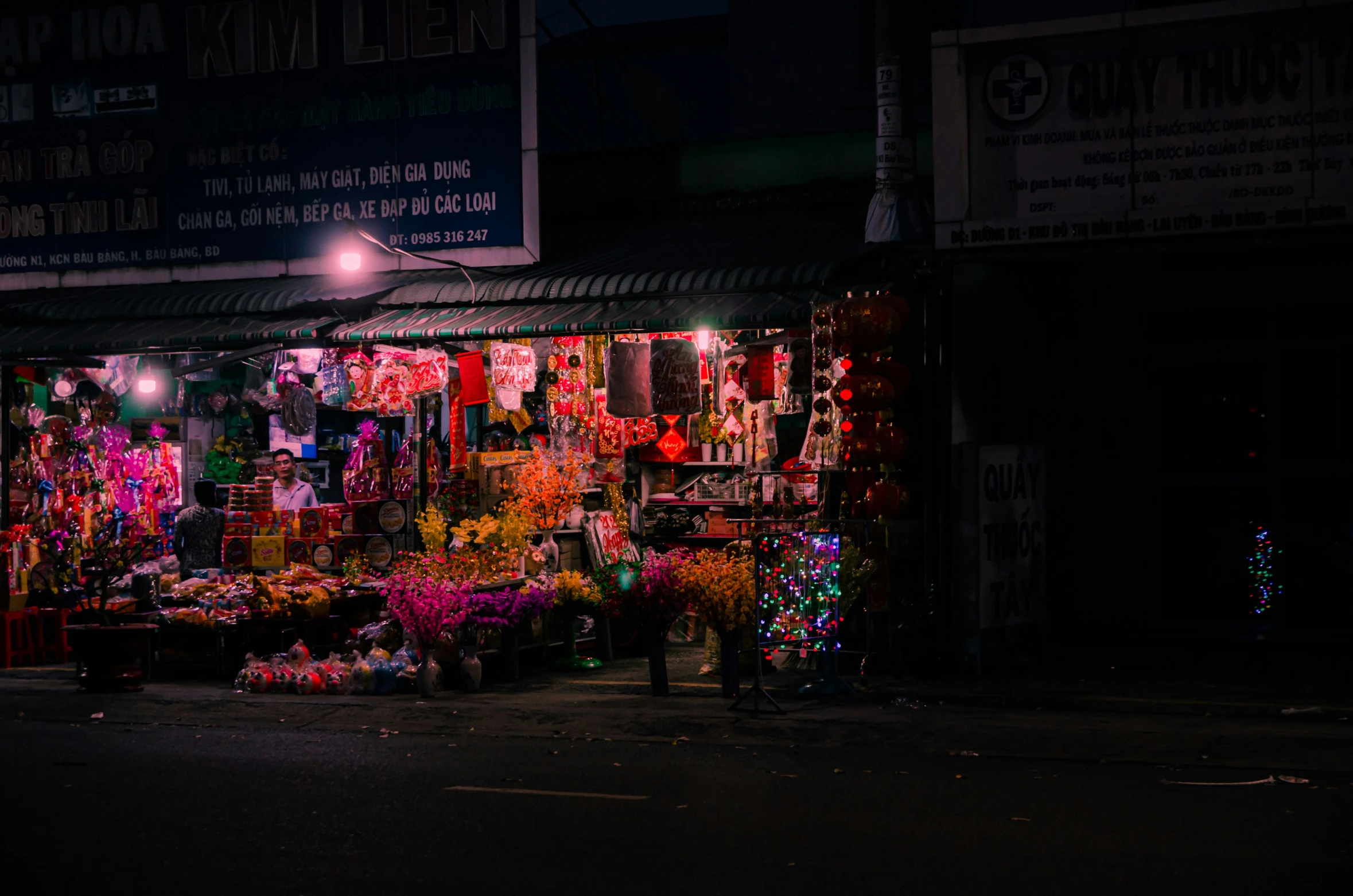 an outdoor market at night with various flowers and lights