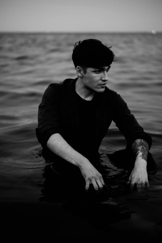 young man sitting in water staring off into the distance