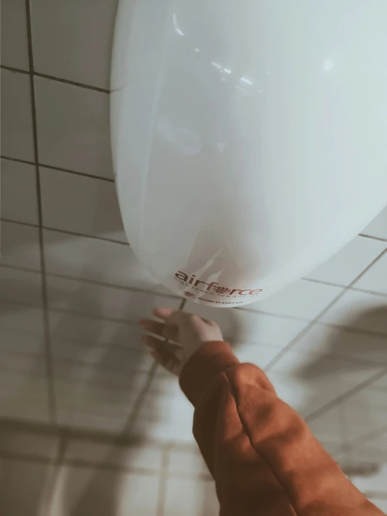 someone reaching for a white balloon in the ceiling