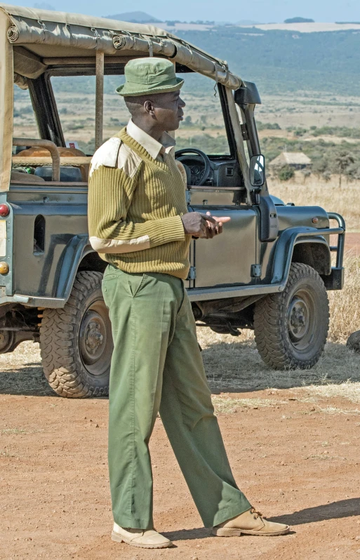 a man standing next to a vehicle on the dirt road