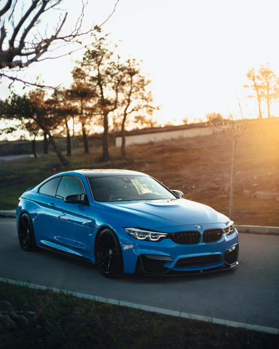 blue bmw gt driving down a road during sunset