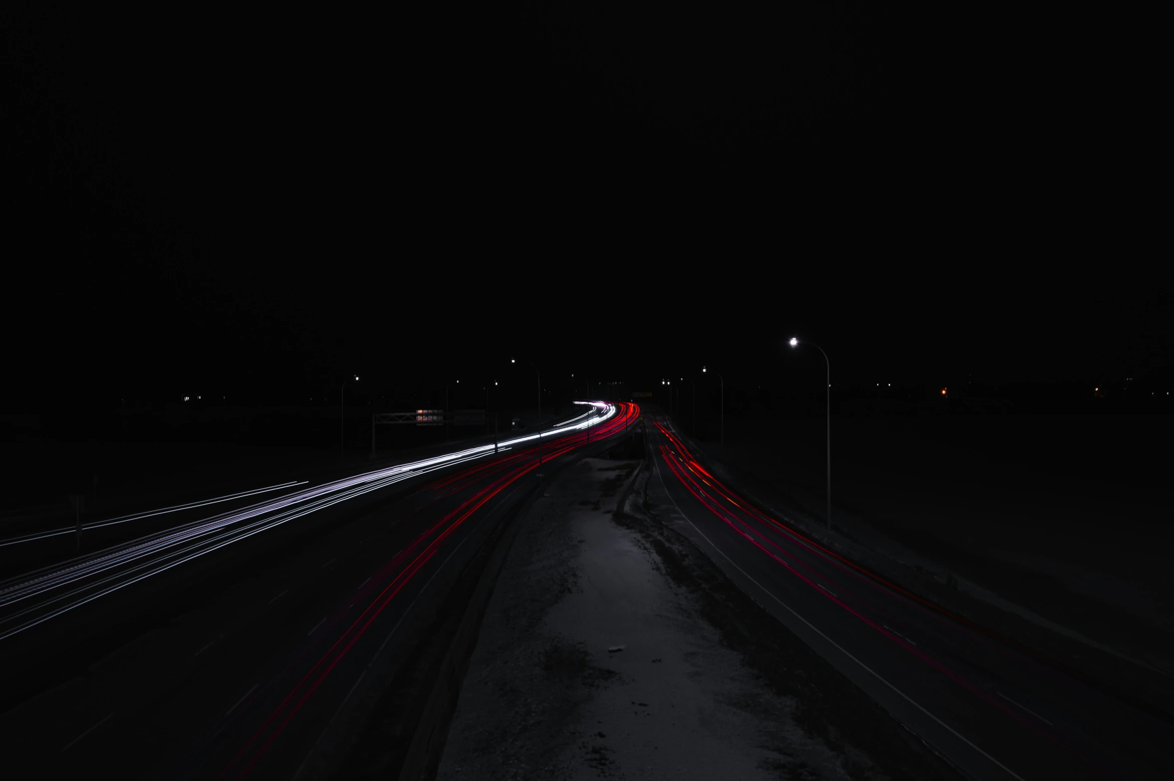 a dark highway filled with cars next to street lights