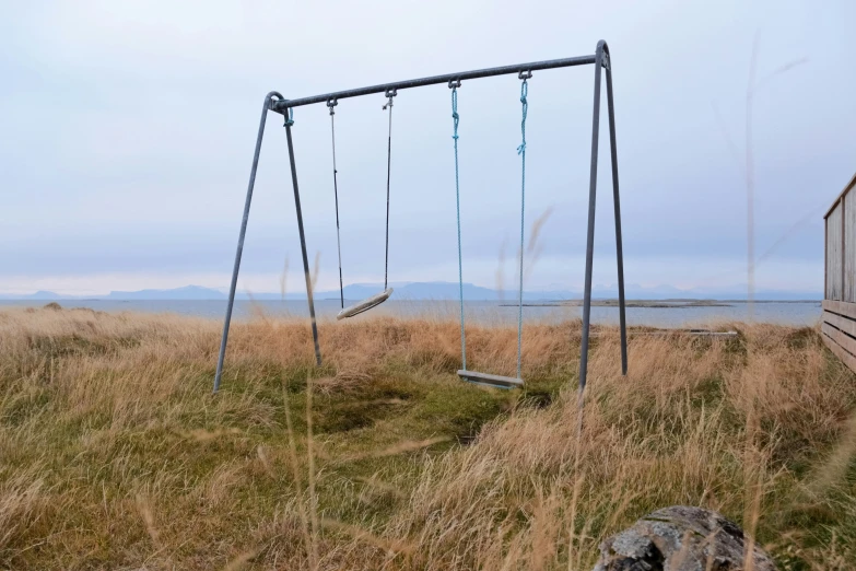 a swingset sitting out on top of a grass covered field